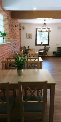 a restaurant with wooden tables and chairs and a brick wall at Przy Dolinie in Paczółtowice