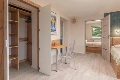 a room with a table and a bedroom with a bed at Apartament Komfort przy Parku Zdrojowym in Rabka