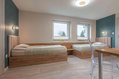 a bedroom with two beds and a table and window at Apartament Komfort przy Parku Zdrojowym in Rabka