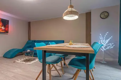 a dining room with a table and blue chairs at Apartament Komfort przy Parku Zdrojowym in Rabka