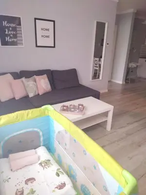 a living room with a couch and a baby crib at Apartament Antek klimatyzowany in Oświęcim