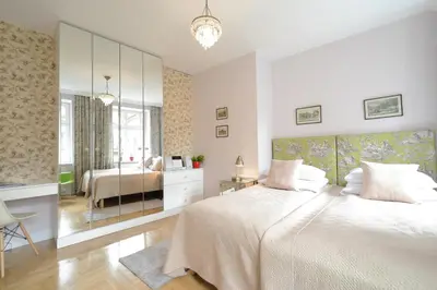 a white bedroom with a bed and a mirror at Crystal Suites Chez Helena in Kraków
