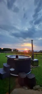 a hot tub in a field with a sunset in the background at Gniewnik in Pcim