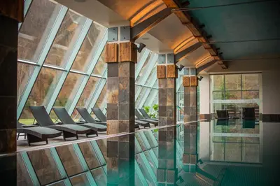 a pool with chairs and windows in a building at Młyn Jacka Hotel & Spa in Wadowice