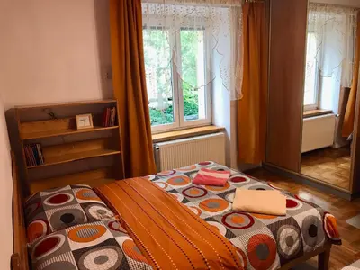 a bedroom with a bed with a comforter and two windows at Sunny apartment. 5 minutes walk from Main Sqare. in Kraków