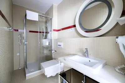 a bathroom with a sink and a shower and a mirror at Home Aparthotel in Kraków
