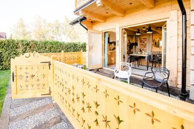 a house with a wooden fence and chairs on a porch at Skansen Holiday in Cholerzyn