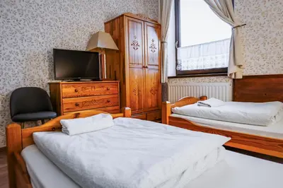 a bedroom with two beds and a tv and a window at Dworek Galicyjski in Oświęcim