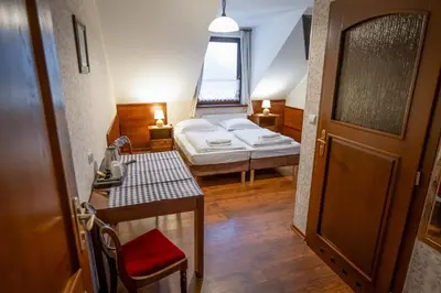 a room with a bed and a table and a door at Dworek Galicyjski in Oświęcim