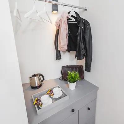 a black leather jacket hanging on a wall above a dresser at Agnes Apartments Old Town in Kraków