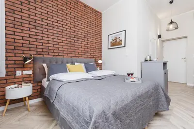 a bedroom with a bed and a brick wall at Agnes Apartments Old Town in Kraków