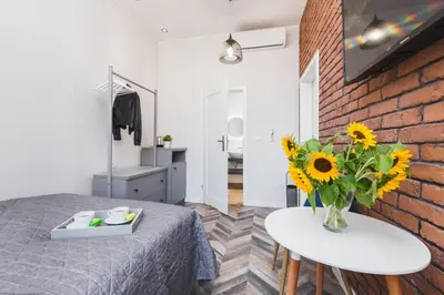 a bedroom with a bed and a table with a vase of sunflowers at Agnes Apartments Old Town in Kraków