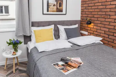 a bedroom with a bed with a brick wall at Agnes Apartments Old Town in Kraków