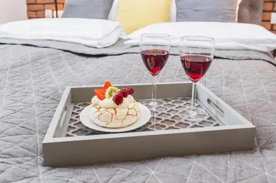 a tray with a plate of food and two glasses of wine at Agnes Apartments Old Town in Kraków