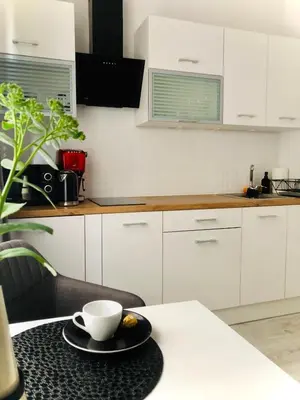 a white kitchen with a table with a cup on it at Nico Apartments in Kraków