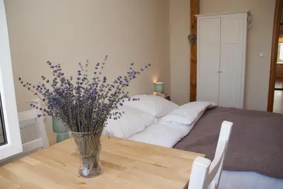 a vase of flowers sitting on a table next to a bed at Lawendowe Siedlisko in Zator