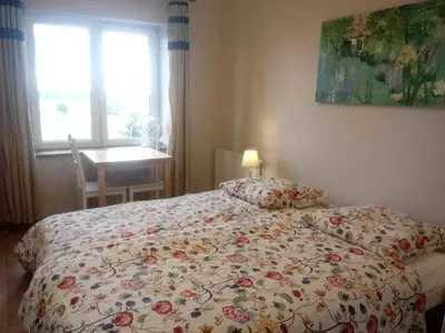 a bedroom with a bed with a floral bedspread and a window at Lawendowe Siedlisko in Zator