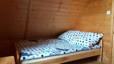 a bed in a room with a wooden wall at Bacówka na Leśnej in Po”łwieś