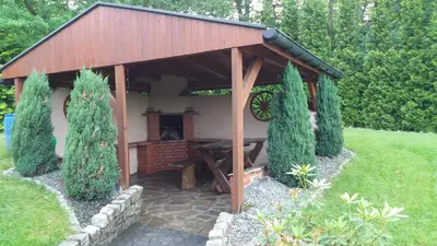 a wooden pavilion with a table in a garden at Bacówka na Leśnej in Po”łwieś