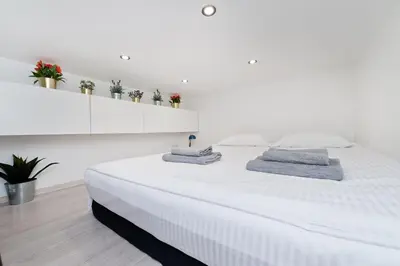a white bed in a white room with plants on a shelf at Dietla 99 - Studio by Homeprime in Kraków