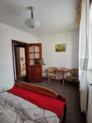 a bedroom with a bed and a table and a door at Dom pod Tujami in Kraków