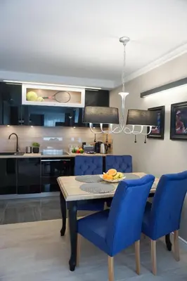 a kitchen and dining room with a table and blue chairs at AGA Tenis Apartments by Radwańska in Kraków