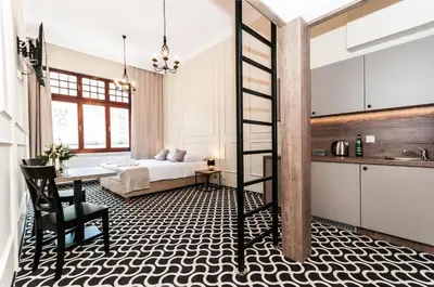 a bedroom with a bed and a desk and a kitchen at Apartamenty L5 in Kraków