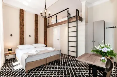 a bedroom with a bed and a desk and a ladder at Apartamenty L5 in Kraków