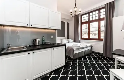 a kitchen with a sink and a bed in a room at Apartamenty L5 in Kraków