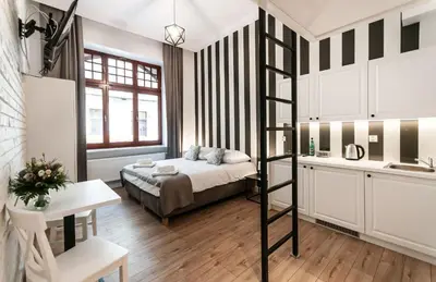 a room with a bed and a ladder in it at Apartamenty L5 in Kraków