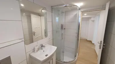 a white bathroom with a shower and a sink at Krakow 360 Apartment in Kraków