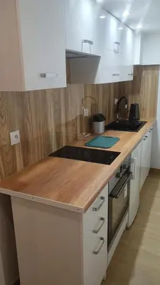 a kitchen with white cabinets and a wooden counter top at Krakow 360 Apartment in Kraków
