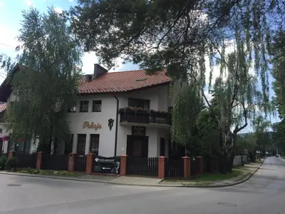 a white building with a balcony on a street at Za Rabą in Myślenice