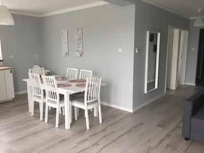 a dining room with a white table and chairs at Apartament Julek klimatyzowany in Oświęcim