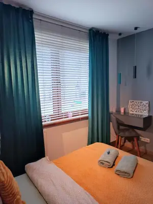 a bedroom with green curtains and a bed with two towels at Dream LUX Apartments in Kraków