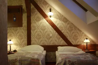 two beds in a attic room with two lamps at Pańska Góra in Jaworzno