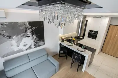 a living room with a chandelier and a blue couch at Crystal Luxury Apartments Rakowicka 22H in Kraków