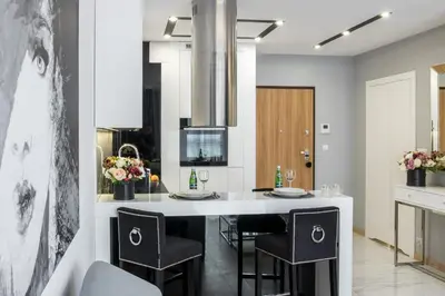 a kitchen with a large white island with black chairs at Crystal Luxury Apartments Rakowicka 22H in Kraków