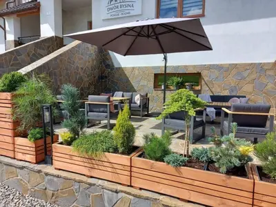 a patio with chairs and an umbrella and plants at Dwór Bysina in Myślenice