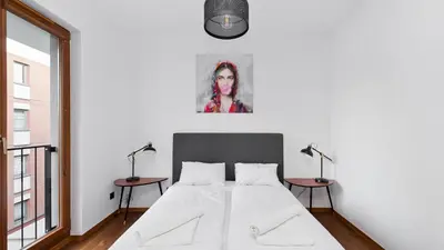 a white bedroom with a bed and two tables at Rakowicka Podkowa City Center, Sun & Snow in Kraków