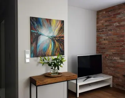 a living room with a tv and a painting on the wall at Wawrzyńca Brick Apartment Kazimierz in Kraków