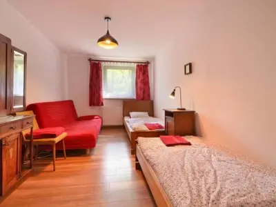 a bedroom with two beds and a red chair at Ranczo Dziki Sad in Raciechowice
