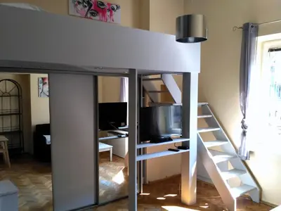 a loft bed with a tv and a desk at Studio Estery in Kraków
