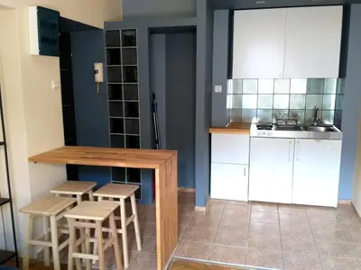 a kitchen with white cabinets and stools and a counter at Studio Estery in Kraków