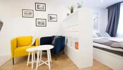 a small room with a bed and a yellow chair and a table at Rakowicka Apartament in Kraków