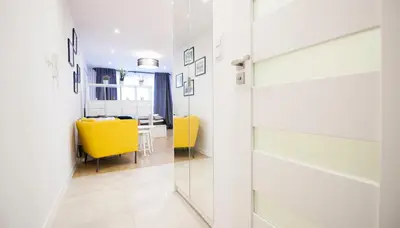 a hallway with yellow chairs and a dining room at Rakowicka Apartament in Kraków