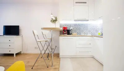 a kitchen with white cabinets and a table and chairs at Rakowicka Apartament in Kraków