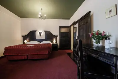 a bedroom with a bed and a dresser and a desk at Hotel Kasztel in Rzezawa