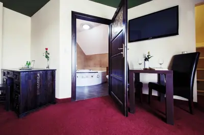 a room with a desk and a table and a television at Hotel Kasztel in Rzezawa