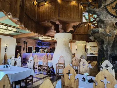 a restaurant with tables and chairs and a large vase at Hotel Kasztel in Rzezawa